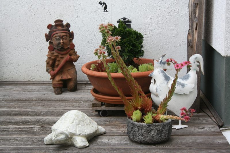 Pflanzen und Skulpturen aus Kulturen Nord- und Südamerikas auf heimischer Terrasse